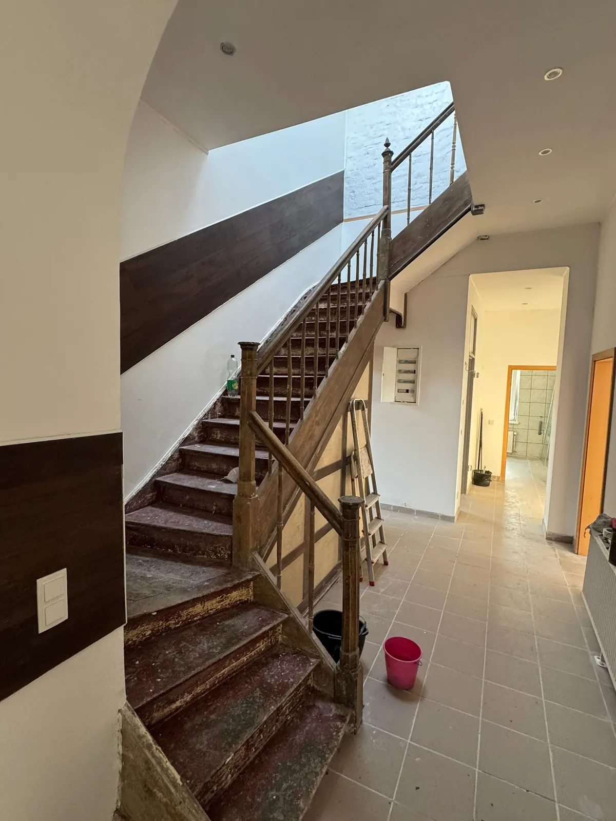 Trappenhal met houten trap, lichte wanden en een dakraam boven de trap